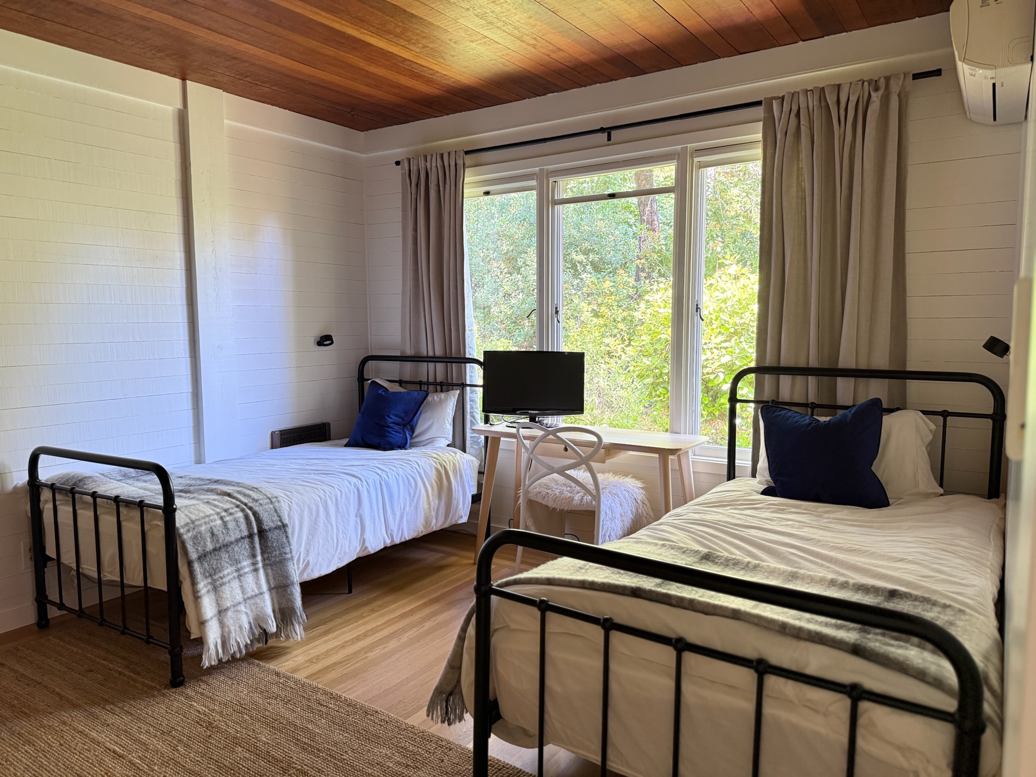 Guest bedroom with twin beds overlooking the oaks — perfect for families, couples, or a tranquil work-from-retreat.
