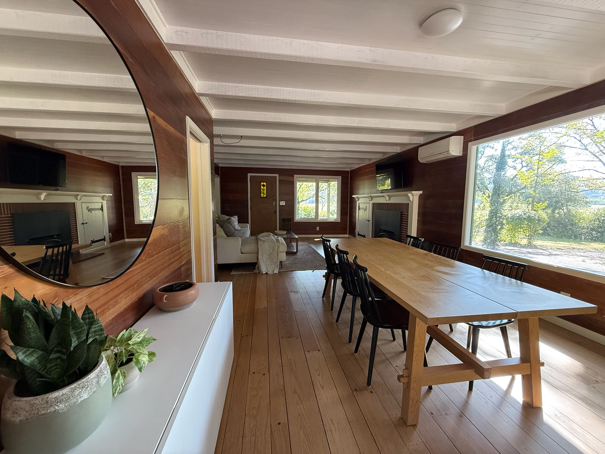 An inviting dining area framed by a wide picture window and warm natural light. The custom oak table comfortably seats eight, blending rustic charm with modern simplicity.
