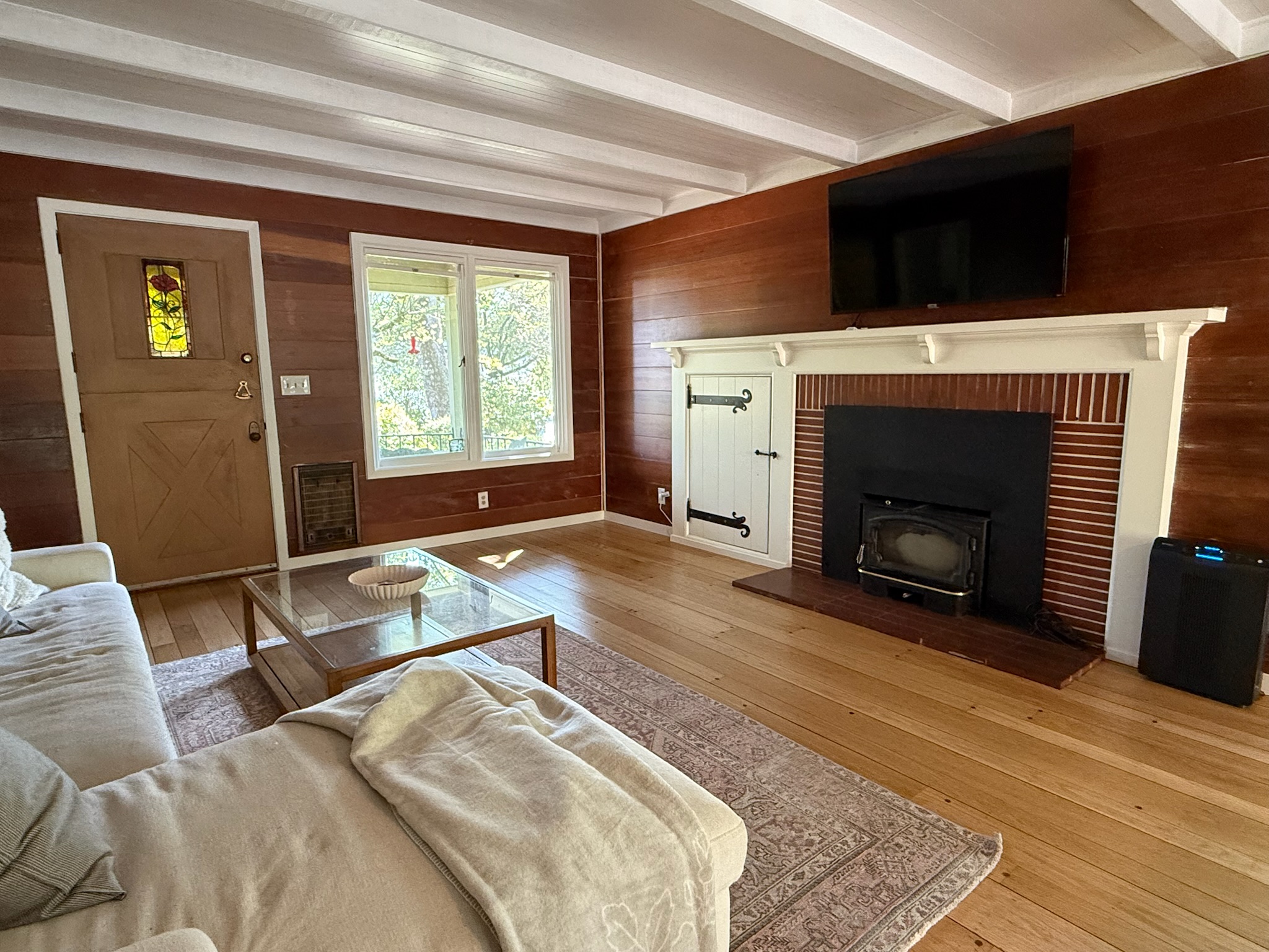 A cozy hearth anchors the living area, featuring a classic wood-burning stove and a mounted flat-screen TV above the elegant white-trimmed fireplace.