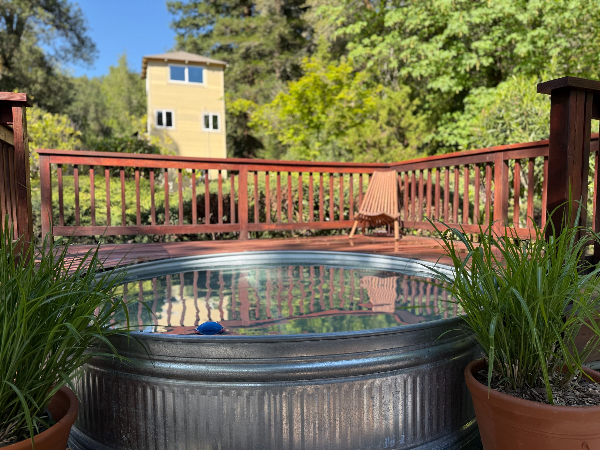 The heated stock tank pool is nestled on its own wooden deck, surrounded by vibrant potted greenery — an idyllic spot for sunrise soaks or starry evening swims.