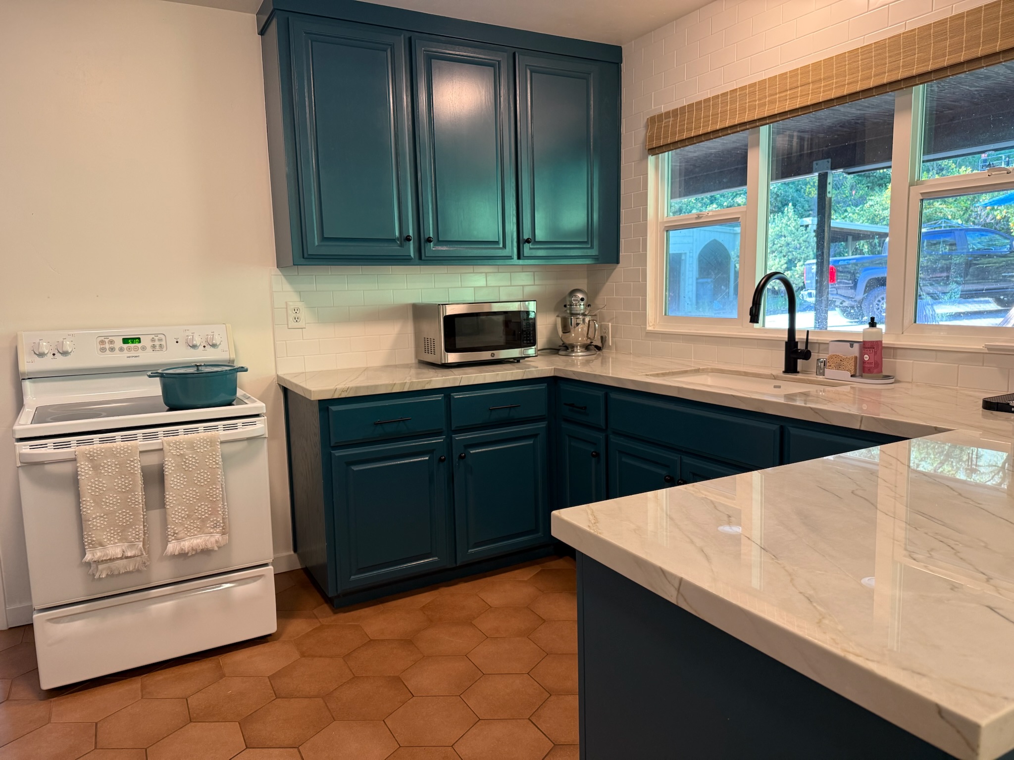 The kitchen is fully equipped with essentials, featuring a full-size oven, a microwave, and a large farmhouse sink paired with a sleek black faucet.