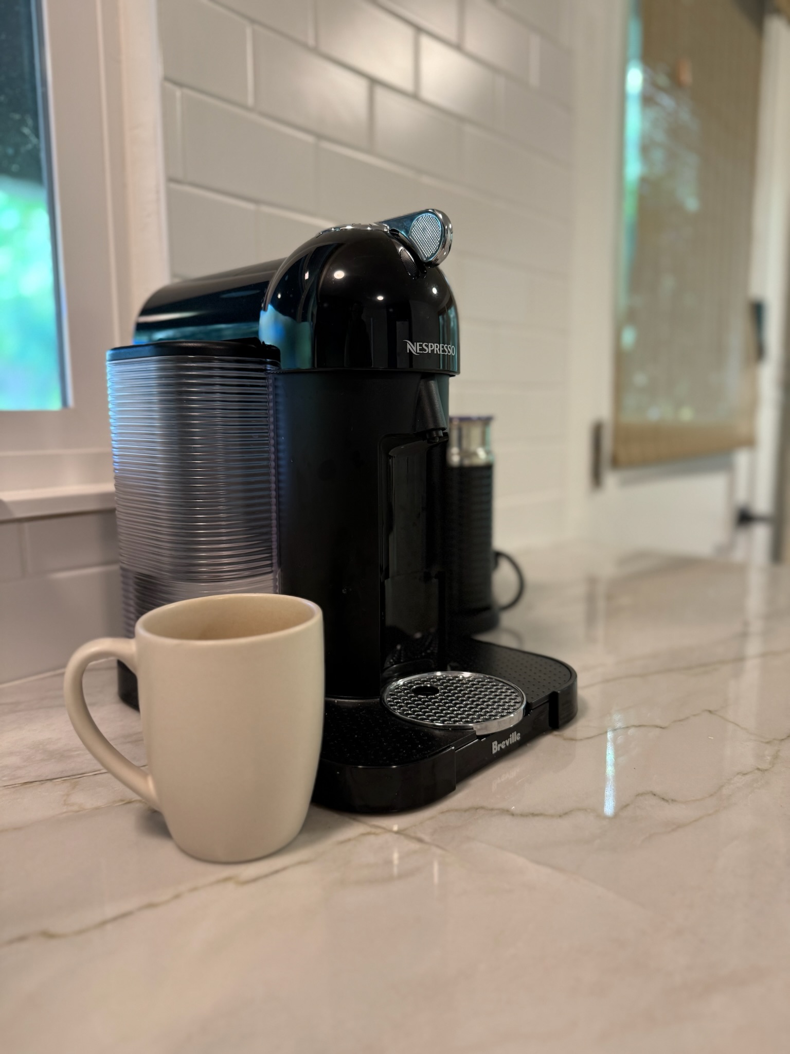 Start your day with a fresh brew from the Nespresso machine, set against gleaming countertops and a bright white subway tile backsplash.